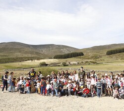 Fotografía de grupo de Su Majestad el Rey junto a alumnos de los CEIP de El Barco de Ávila y de Hoyos del Espino, a su llegada al Refugio "El Mel