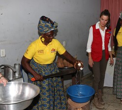 Una mujer de un puesto abre un coco en presencia de Su Majestad la Reina