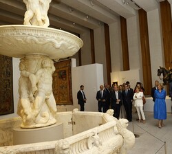 Sus Majestades los Reyes observan una fuente durante el recorrido por la Galería