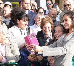 Su Majestad la Reina se fotografía con una niña a su salida del acto