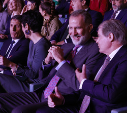 Su Majestad el Rey sentado entre el público, conversa con el presidente de la FPdGi