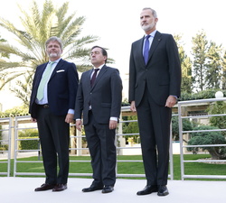 Su Majestad el Rey durnate la interpretación del Himno Nacional, acompañado por el ministro de Asuntos Exteriores, Unión Europea y Cooperación y el em