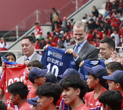 Fotografía de grupo de Su Majesdtad el Rey, con la camisata del equipo local, y las autoridades y los niños beneficiarios del programa escuelas de fút