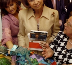 Doña Sofía observa un libro durante su visita a la Feria del Libro