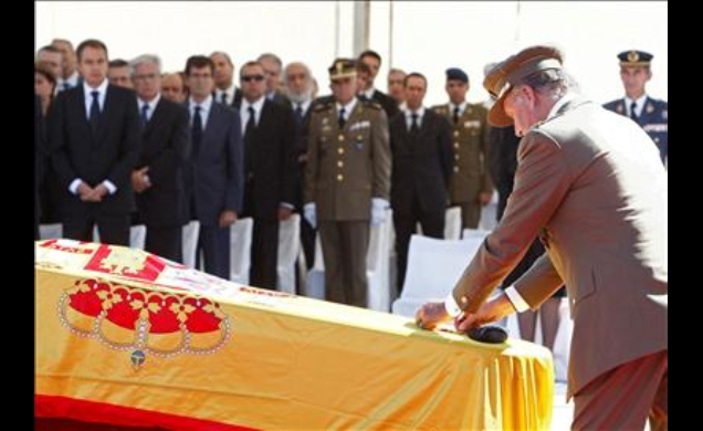 Don Juan Carlos impone la Medalla al Mérito Militar con distintivo rojo, concedida a título póstumo, sobre los féretros con los restos mortales de los