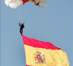 Uno de los miembros de la Patrulla Acrobática Paracaidista del Ejército del Aire (PAPEA) hace ondear la bandera española en el cielo de Madrid, durant