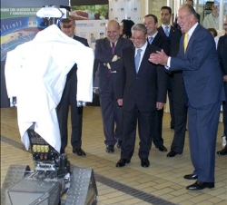 El Rey observa a un robot durante su visita a las instalaciones, en presencia del presidente de Puleva Biotech