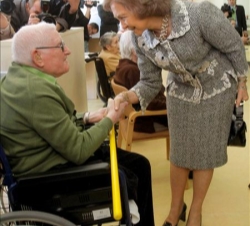 La Reina saluda a un anciano durante su recorrido por el hospital