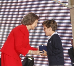 La Reina entrega el premio a uno de los niños ganadores en el concurso
