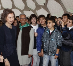 La Reina acompañada por el profesor Yunus conversan con un grupo de escolares