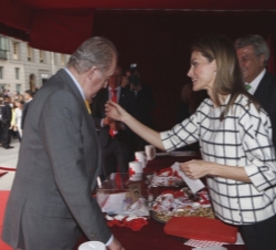 Doña Letizia coloca a Don Juan Carlos la pegatina con motivo del donativo realizado