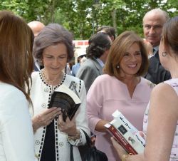 Su Majestad la Reina Doña Sofía hojea un libro durante su recorrido por la Feria del Libro de Madrid