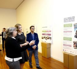 Doña Letizia atiende a las explicaciones de la delegada en el País Vasco y el presidente de FEDER durante su recorrido por la exposición informativa s