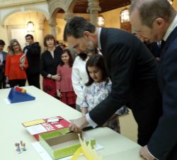 Su Majestad el Rey observa el trabajo de la niña ganadora, Ana Tárregas Garré, por la Región de Murcia