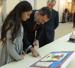 Su Majestad el Rey observa el trabajo de la niña ganadora, Sheila Hammu Mohamed, por la Ciudad Autónoma de Melilla