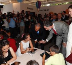 Sus Majestades los Reyes y el Presidente de Portugal conversan con unos niños durante su visitan el Pabellón de Samsung en la Feria del Libro de Madri