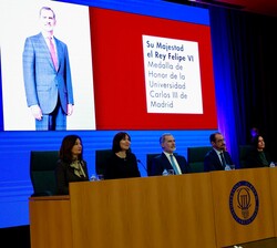 Su Majestad el Rey en la mesa presidencial durante la proyección del como galardonado con la Medalla de Honor de la Universidad Carlos III