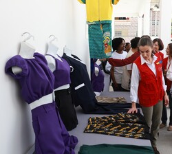 La Reina recorre una pequeña exposición de prendas realizadas por mujeres beneficiarias del proyecto