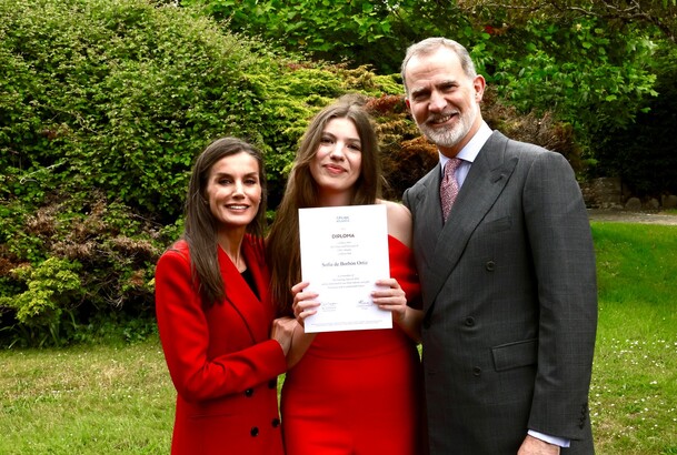 Fotografía de familia de Sus Majestades los Reyes y Su Alteza Real la Infanta Sofía mostrando orgullosa su diploma de Bachillerato Internacional