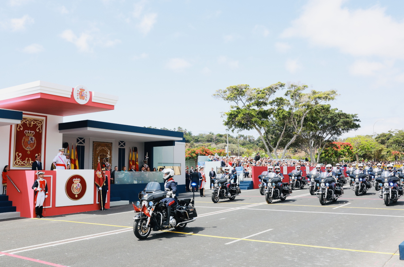 Sus Majestades los Reyes en la Tribuna Real al paso de una sección de motos de la Guardia Real 