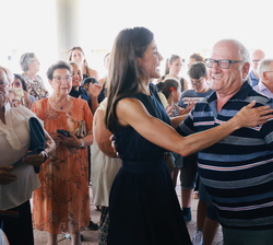 Su Majestad la Reina recibe un caluroso saludo de uno de los miembros del grupo motor del 50º aniversario, formado por personas de entre 60 y 90 años 