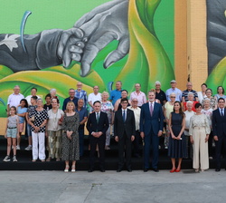 Fotografía de grupo de Sus Majetades los Reyes con una representación debadienses frente al mural participativo que rinde homenaje a Badia del Vallès