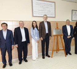 Sus Majestades los Reyes acompañados de las autoridades asistentes al acto ante una placa conmemorativa de su visita