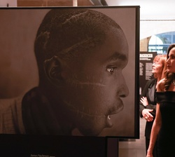 Su Majestad la Reina observa una de las fotografías de la exposición