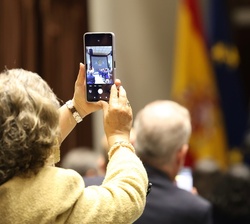 Un asistente al acto refleja en su teléfono móvil a Don Felipe en sus palabras