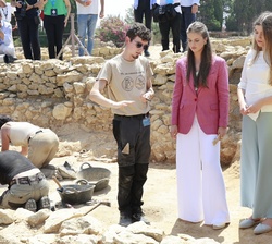 Sus Altezas Reales reciben información sobre el avance de la excavación por parte de uno de los alumnos del curso de arqueología. 