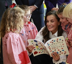 Momento de risas entre Doña Letizia y los alumnos mientras hojean el libro que le han regalado