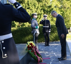 Sus Majestades los Reyes frente a la Cruz de los Héroes durante la ofrenda floral