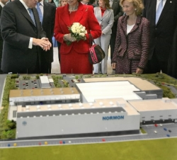 La Reina atiende a la explicación del presidente de Laboratorios Normon sobre una maqueta de las nuevas instalaciones
