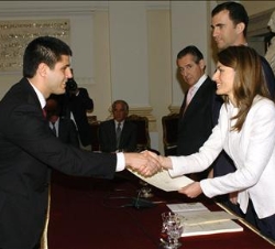 La Princesa hace entrega de su diploma a un joven universitario, en presencia de Don Felipe