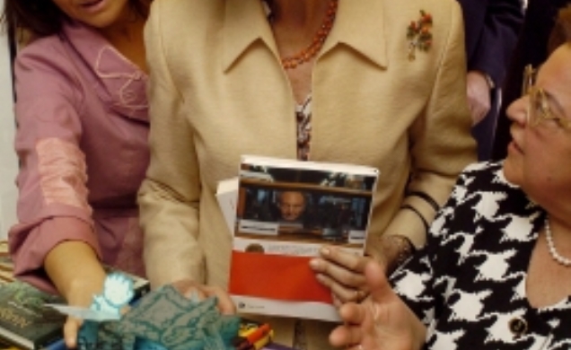 Doña Sofía observa un libro durante su visita a la Feria del Libro